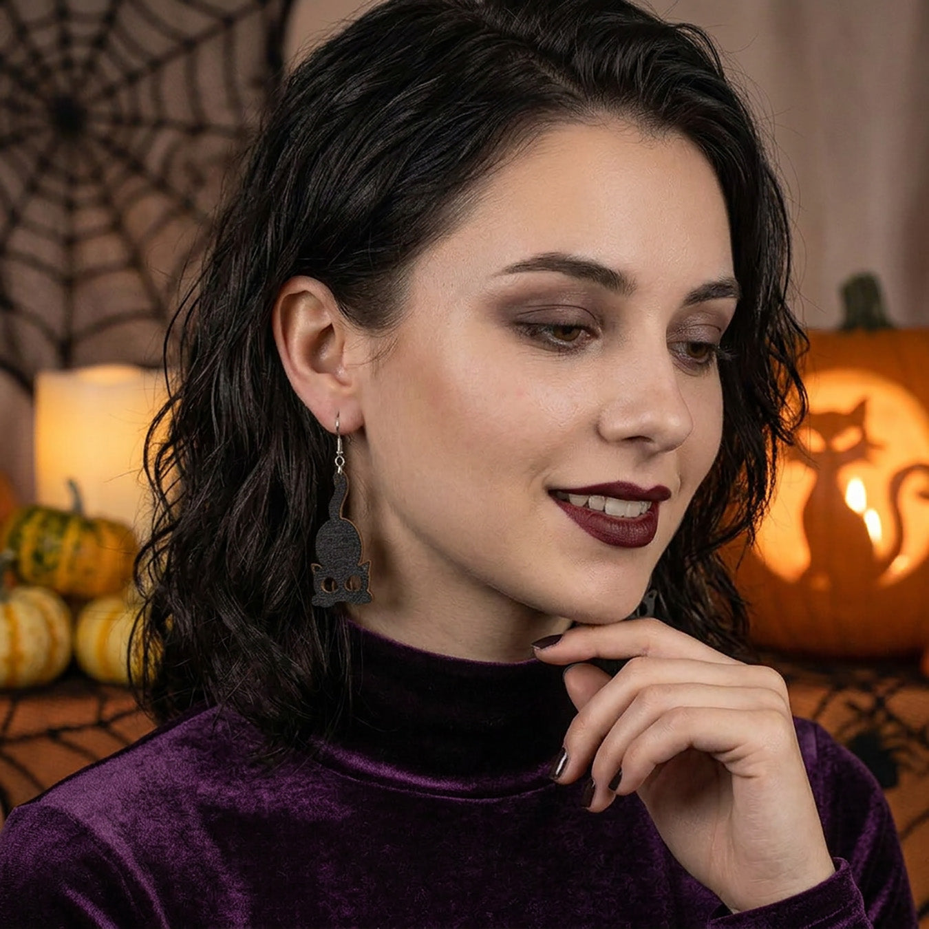 Woman wearing Black Cat Earrings in a cozy Halloween setting.