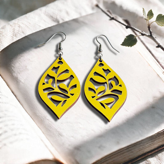 Yellow Vine plywood earrings made in Finland, photographed on a vintage book in natural sunlight