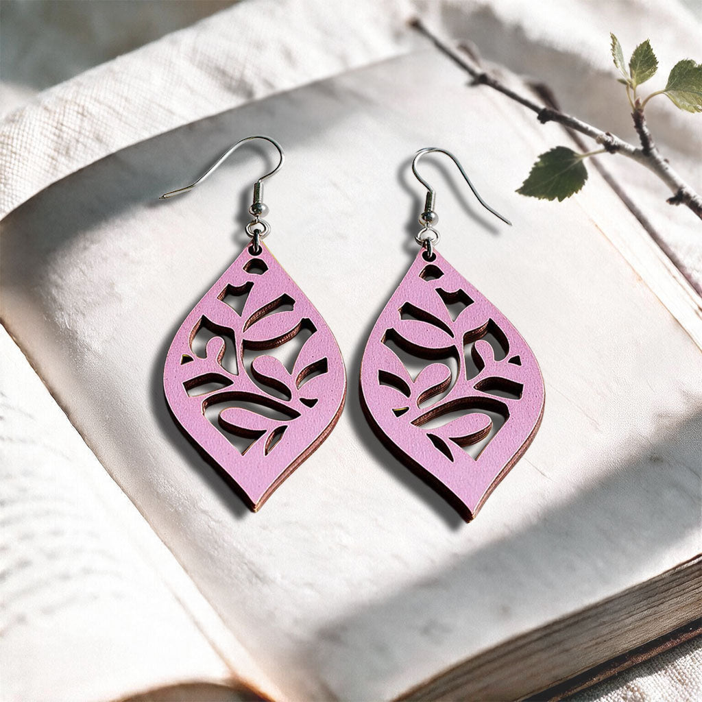 Mauve Vine plywood earrings made in Finland, photographed on a vintage book in natural sunlight
