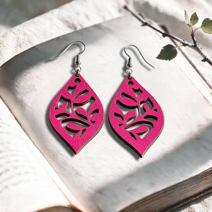 Raspberry Vine plywood earrings made in Finland, photographed on a vintage book in natural sunlight