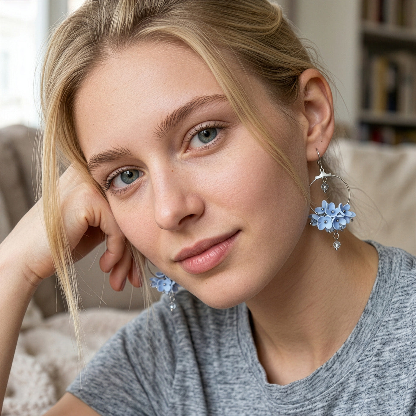 Woman wearing Light Blue Flower Vine Hoop Earrings in a soft summer garden. Handmade floral earrings inspired by the clear blue tones of the summer sky.
