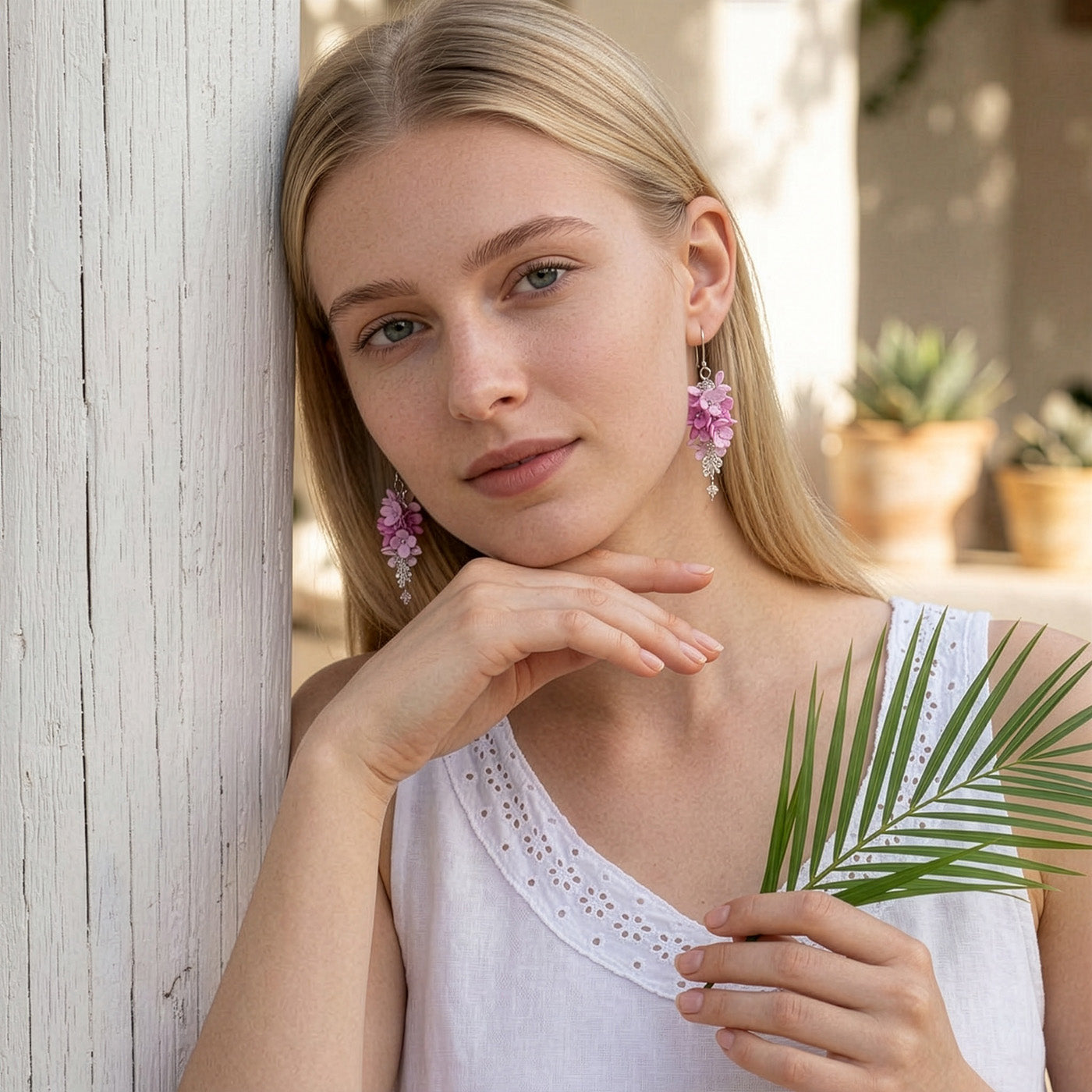 Woman wearing Flower Cloud Earrings in a sunlit summer garden. Handmade floral earrings inspired by blooming pink flowers and the softness of a Finnish summer.