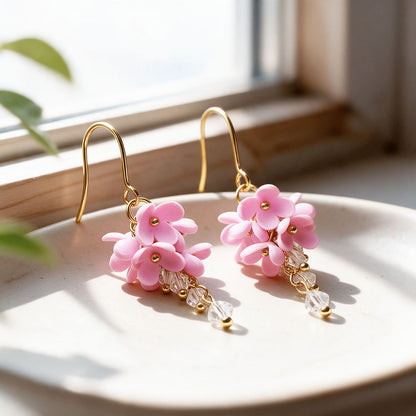 Pink flower earrings with gold-plated details and clear crystals, photographed in natural sunlight, handmade in Finland