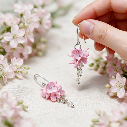 Pink Kukkaverso flower earrings handmade in Finland, photographed with pale pink flowers in natural light