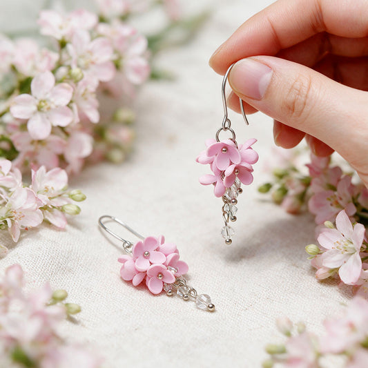 Pink Kukkaverso flower earrings handmade in Finland, photographed with pale pink flowers in natural light