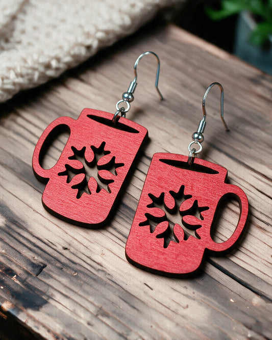 Christmas hot drink cup earrings made in Finland, photographed on a wooden table in natural light