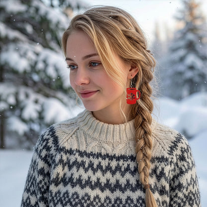 Blonde woman wearing red mug earrings in a snowy winter landscape, dressed in a warm Nordic knit sweater. Handmade in Finland by byMinta.