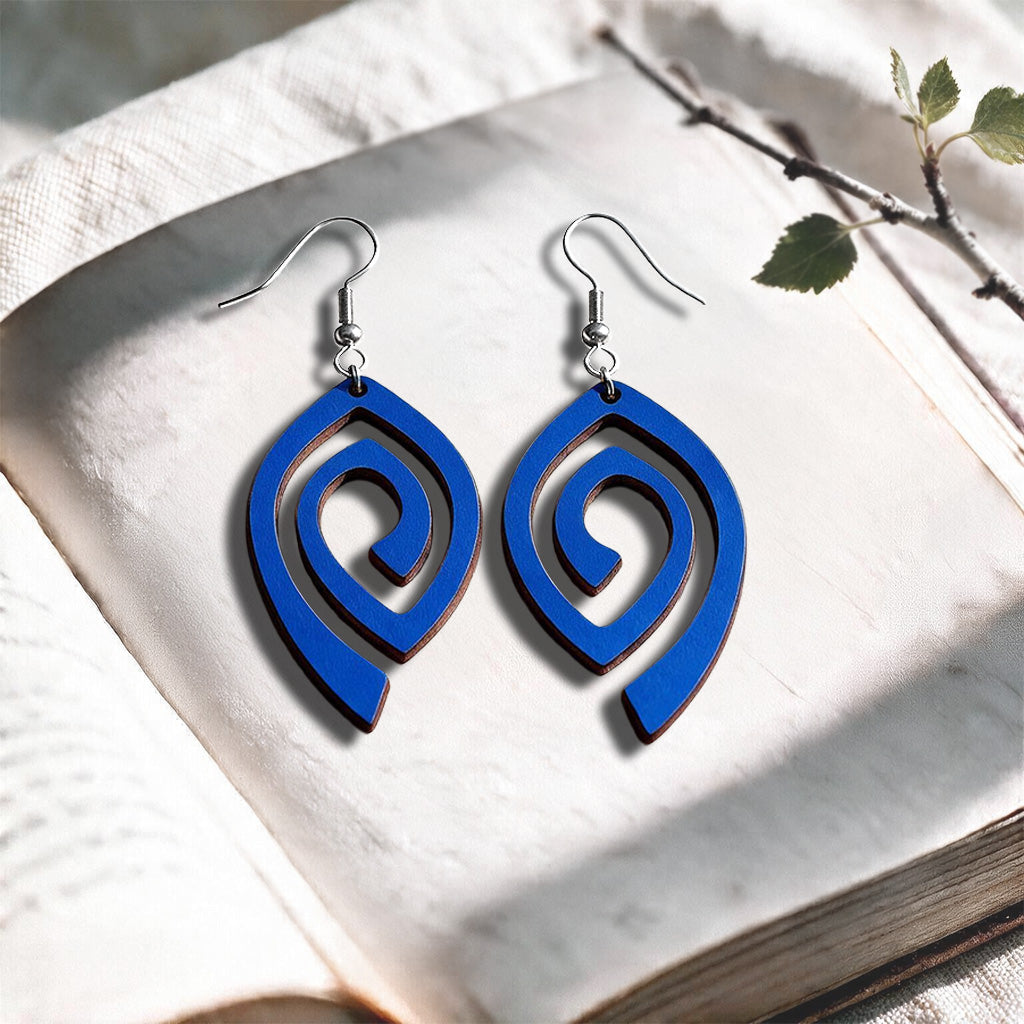 Electric Blue Labyrinth plywood earrings made in Finland, photographed on a vintage book in natural sunlight