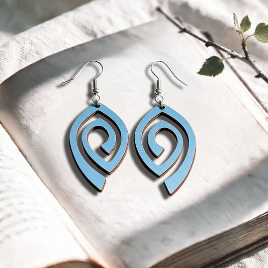 Light Blue Labyrinth plywood earrings made in Finland, photographed on a vintage book in natural sunlight