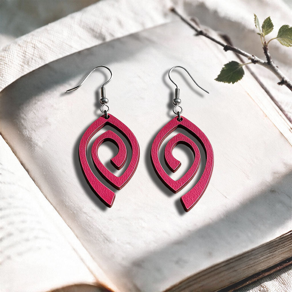 Raspberry Labyrinth plywood earrings made in Finland, photographed on a vintage book in natural sunlight
