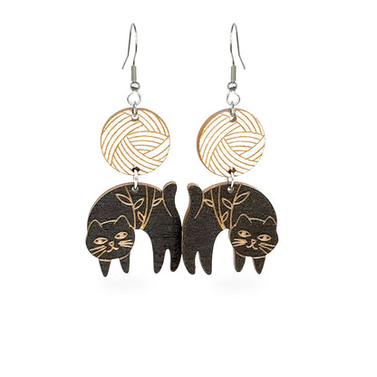 Handmade black cat earrings with engraved botanical details and geometric wooden top pieces. Lightweight Finnish birch plywood statement earrings inspired by curious cats and Nordic design.