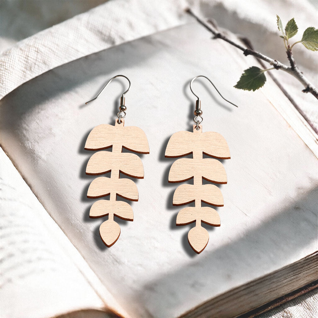 Nude Leaflet plywood earrings made in Finland, photographed on a vintage book in natural sunlight
