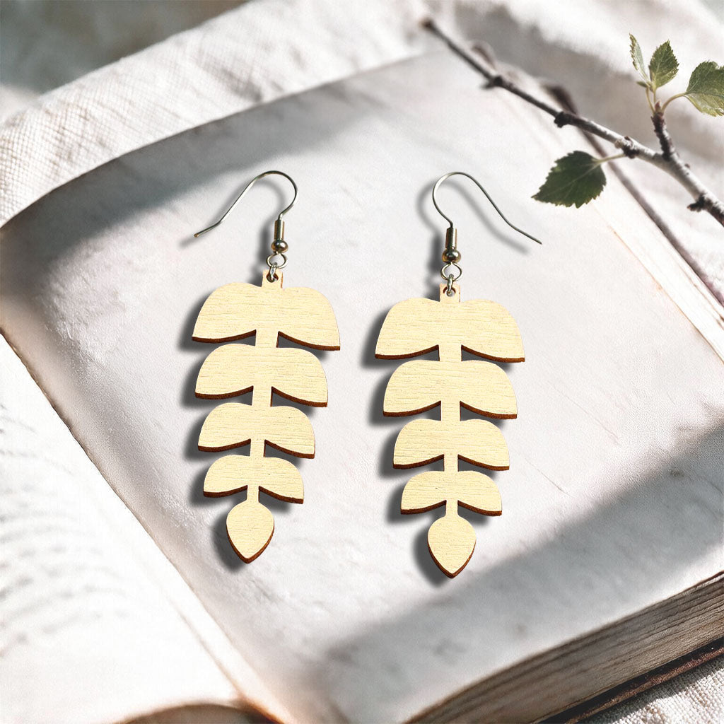 Vanilla Leaflet plywood earrings made in Finland, photographed on a vintage book in natural sunlight