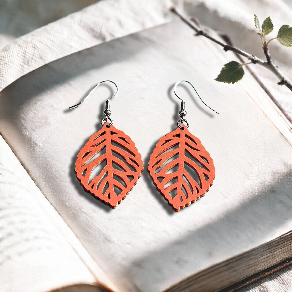 Coral Leaf plywood earrings made in Finland, photographed on a vintage book in natural sunlight