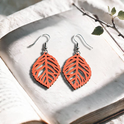 Coral Leaf plywood earrings made in Finland, photographed on a vintage book in natural sunlight