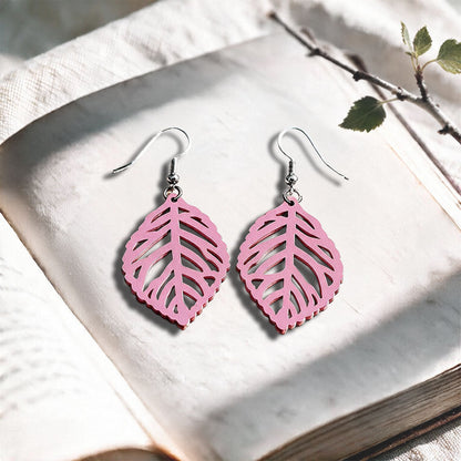 Mauve Leaf plywood earrings made in Finland, photographed on a vintage book in natural sunlight