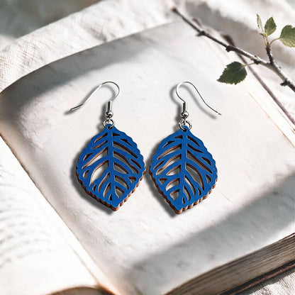 Blue Leaf plywood earrings made in Finland, photographed on a vintage book in natural sunlight
