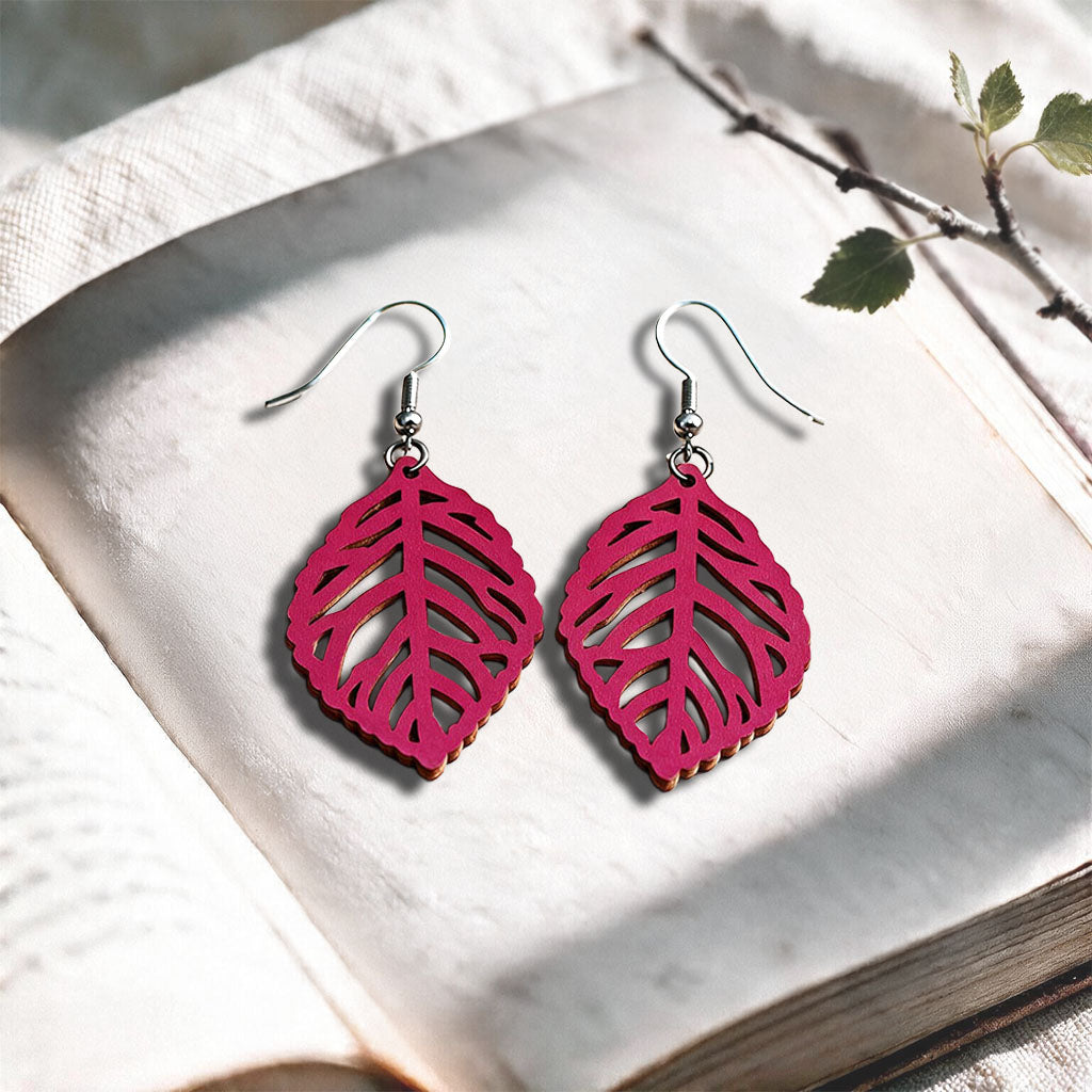 Raspberry Leaf plywood earrings made in Finland, photographed on a vintage book in natural sunlight