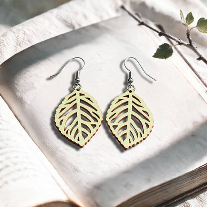 Vanilla Leaf plywood earrings made in Finland, photographed on a vintage book in natural sunlight