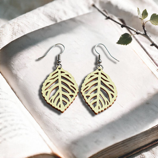 Vanilla Leaf plywood earrings made in Finland, photographed on a vintage book in natural sunlight