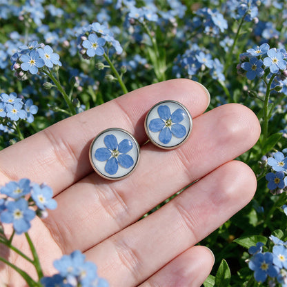 Hand holding handmade forget-me-not stud earrings with real blue forget-me-not flowers preserved in resin