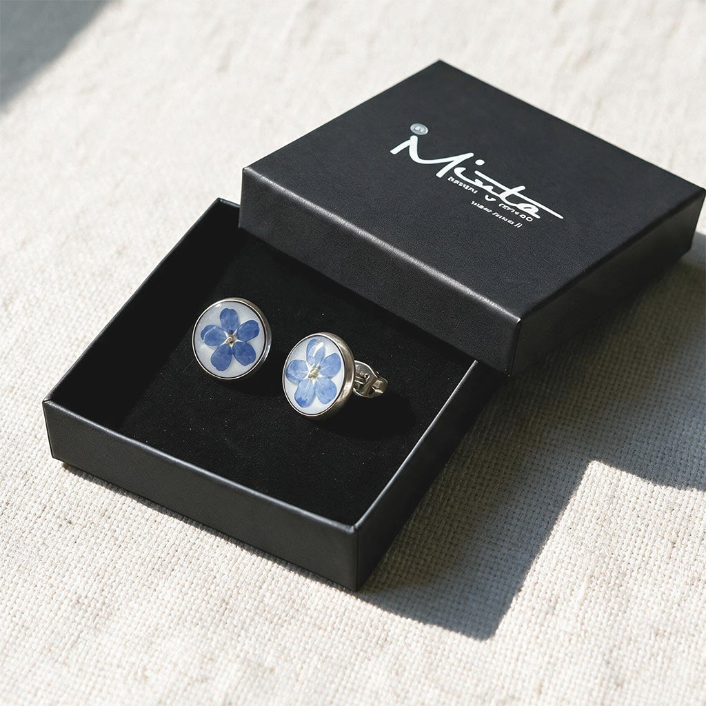 Black jewelry box with handmade forget-me-not stud earrings featuring real blue flowers preserved in resin