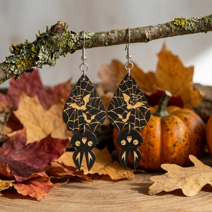 Spider Web Bat Earrings hanging from a moss-covered branch in an autumn setting.