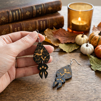 Hand holding lightweight Spider Web Bat Earrings for size reference.