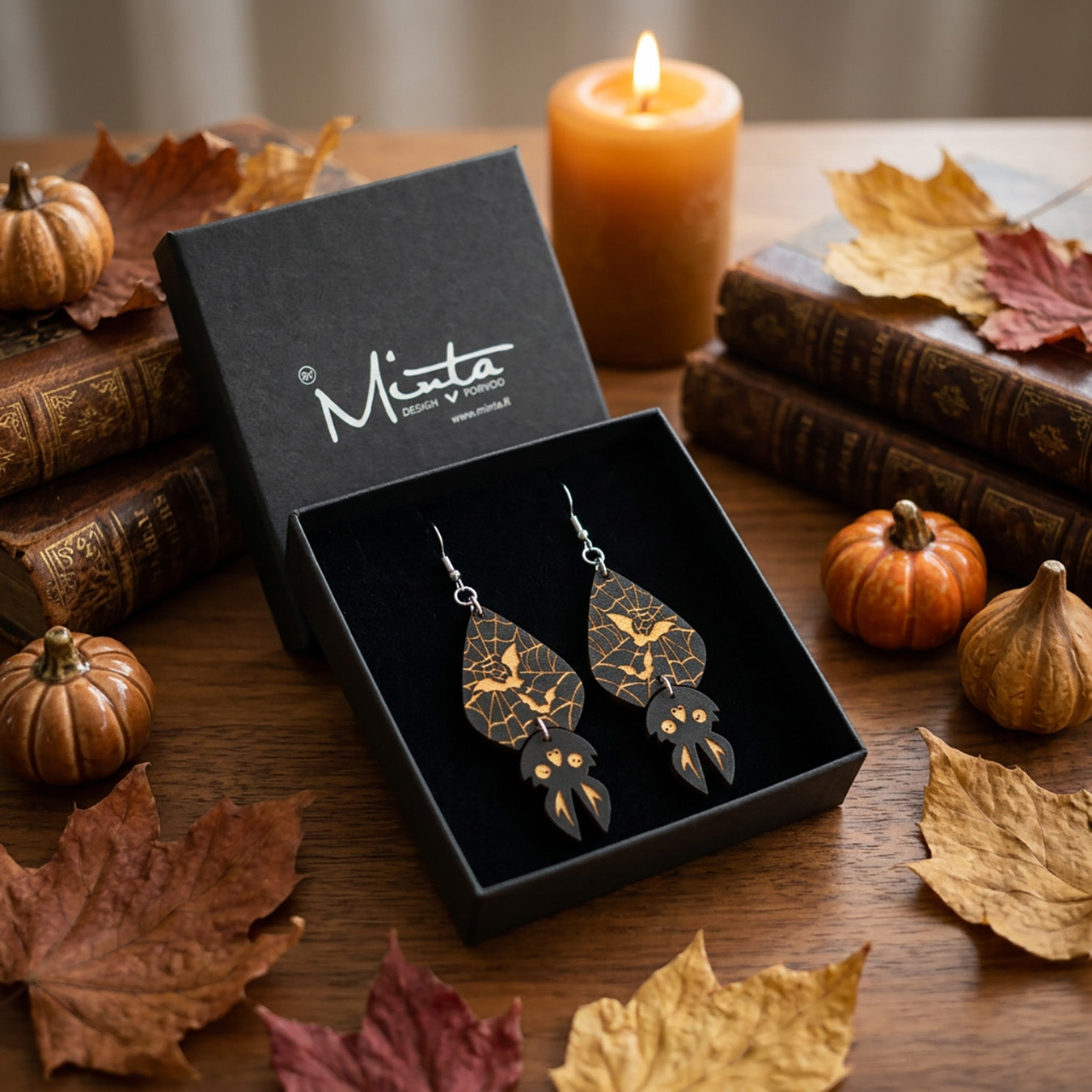 Spider Web Bat Earrings in byMinta gift box surrounded by autumn leaves and pumpkins.