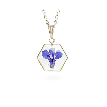 Lobelia Necklace with a real blue lobelia flower preserved in clear resin inside a gold-plated hexagon pendant, handmade in Finland by byMinta