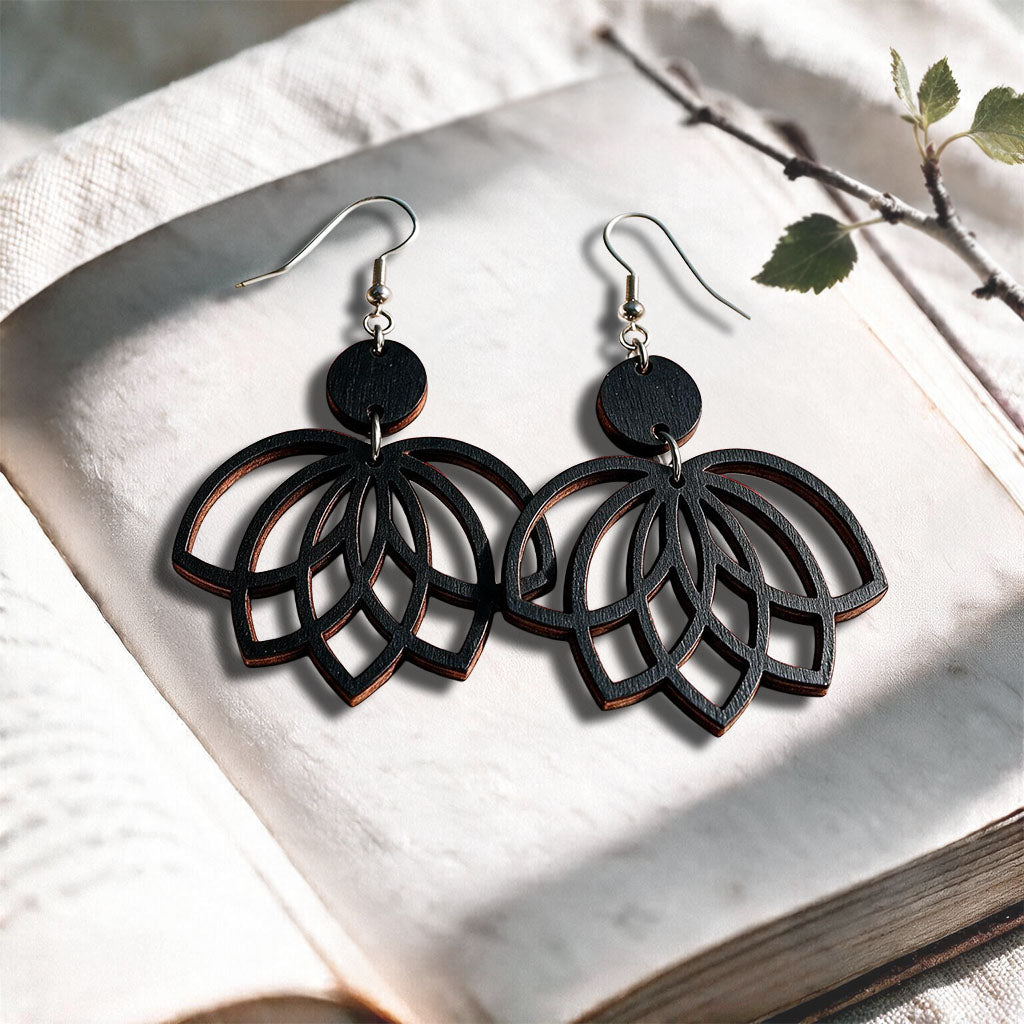 Black plywood earrings made in Finland, photographed on a vintage book in natural sunlight