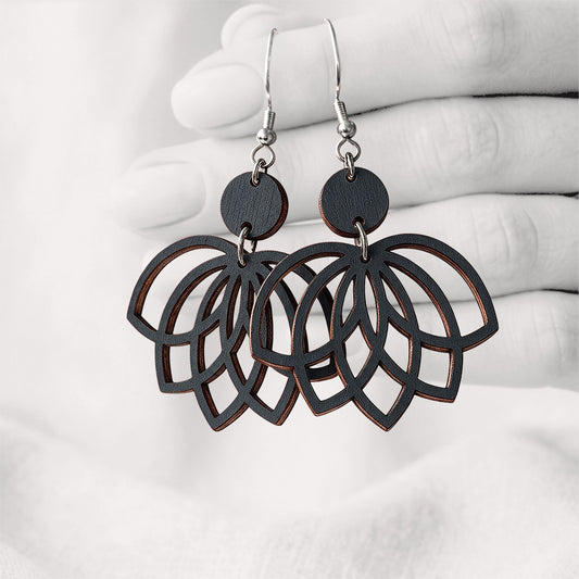 Black plywood earrings made in Finland, photographed on a vintage book in natural sunlight