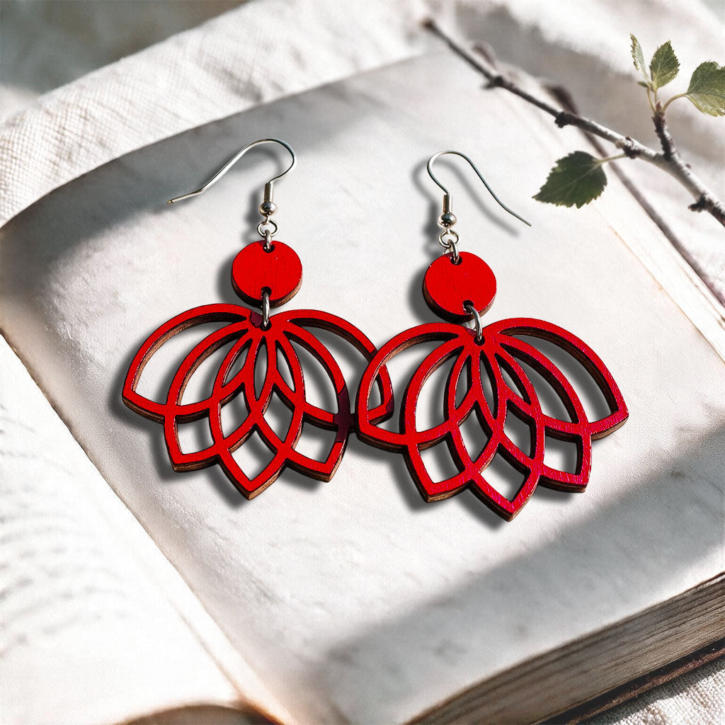 Red Lotus plywood earrings made in Finland, photographed on a vintage book in natural sunlight