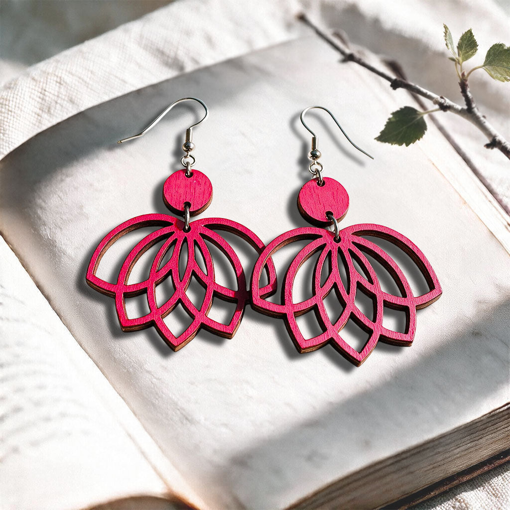 Raspberry plywood earrings made in Finland, photographed on a vintage book in natural sunlight