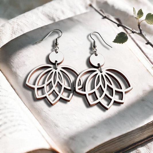 White Lotus plywood earrings made in Finland, photographed on a vintage book in natural sunlight