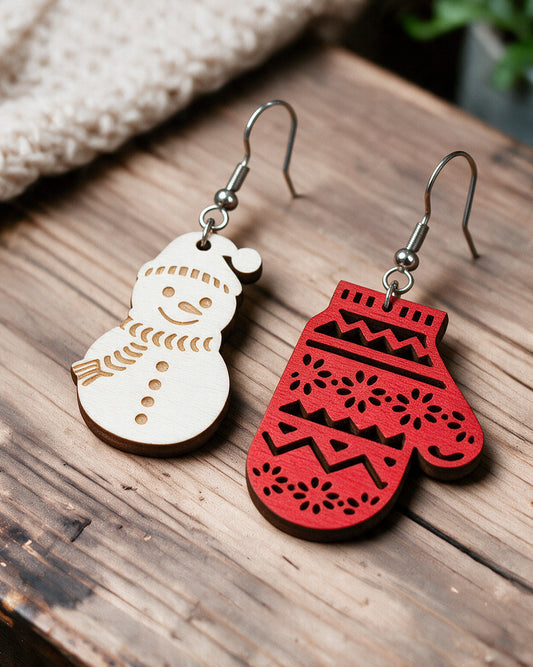 Snowman and mitten Christmas earrings made in Finland, photographed on a wooden table in natural light