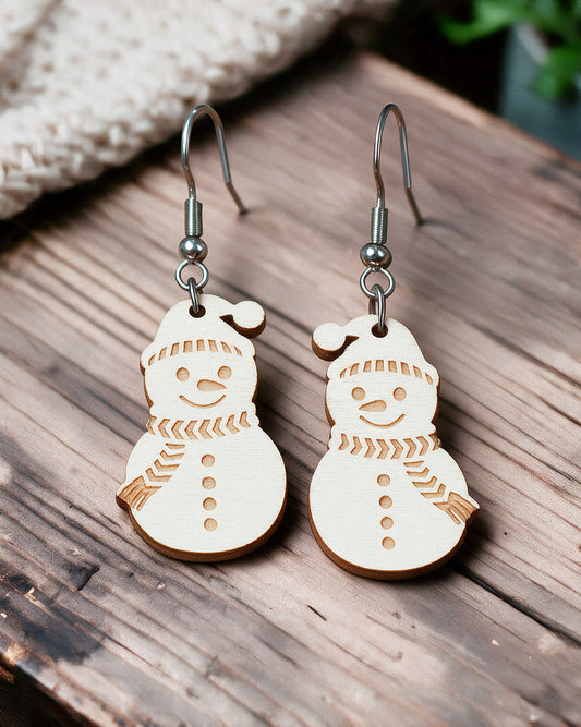 Snowman Christmas earrings made in Finland, photographed on a wooden table in natural light