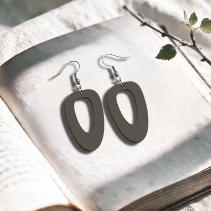 Grey wood Islet plywood earrings made in Finland, photographed on a vintage book in natural sunlight