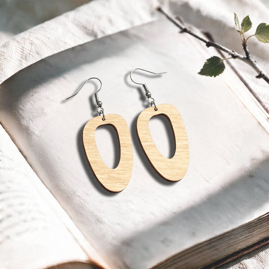 Natural wood Islet plywood earrings made in Finland, photographed on a vintage book in natural sunlight