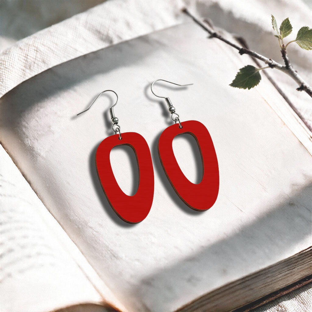 Red Islet plywood earrings made in Finland, photographed on a vintage book in natural sunlight