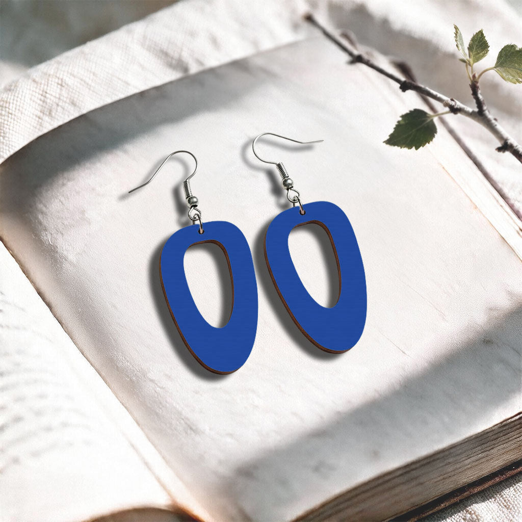 Blue Islet plywood earrings made in Finland, photographed on a vintage book in natural sunlight
