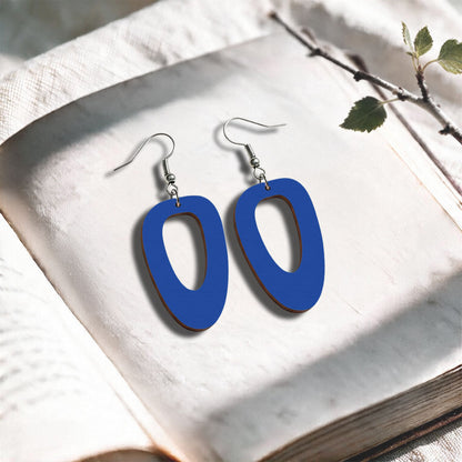 Blue Islet plywood earrings made in Finland, photographed on a vintage book in natural sunlight