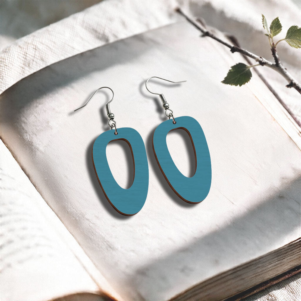 Skyblue Islet plywood earrings made in Finland, photographed on a vintage book in natural sunlight