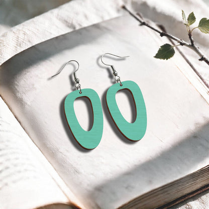 Turquoise Islet plywood earrings made in Finland, photographed on a vintage book in natural sunlight