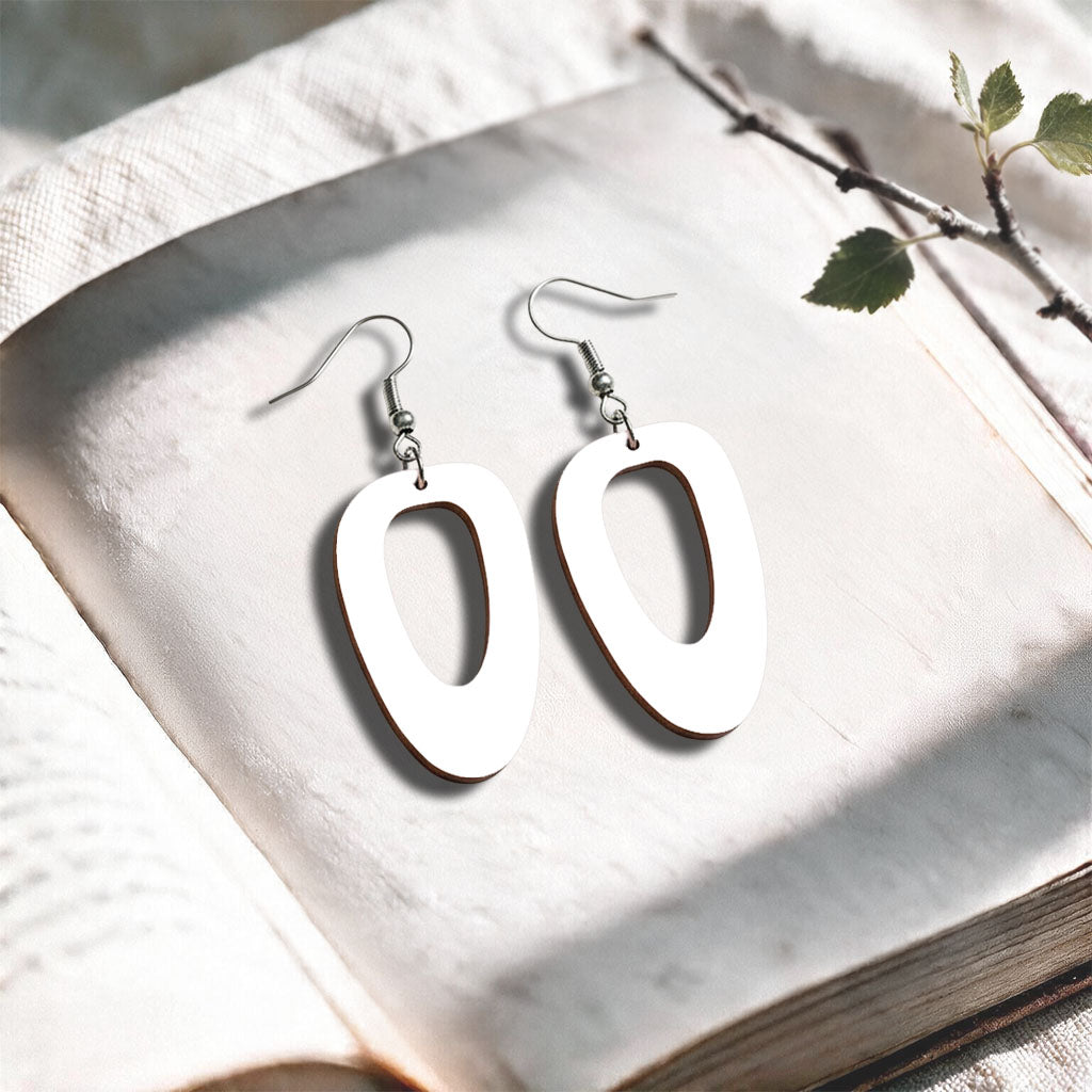 White Islet plywood earrings made in Finland, photographed on a vintage book in natural sunlight