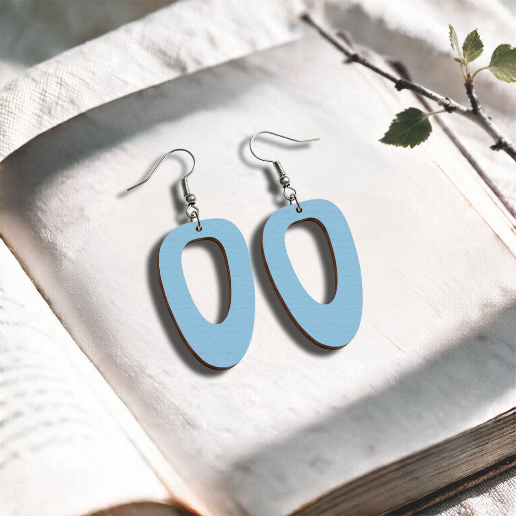 Light blue plywood earrings made in Finland, photographed on a vintage book in natural sunlight
