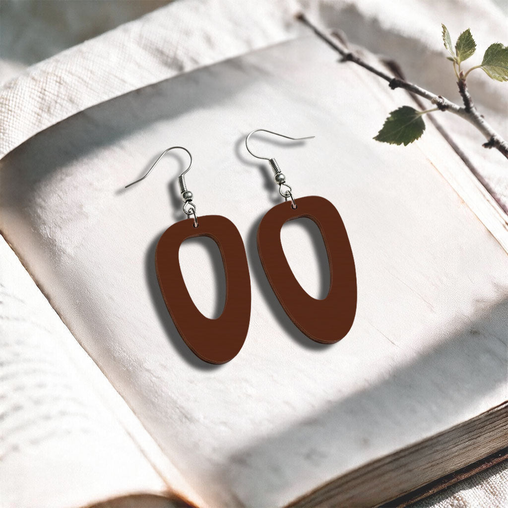 Walnut Islet plywood earrings made in Finland, photographed on a vintage book in natural sunlight