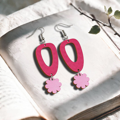 Raspberry and mauve Islet Flower plywood earrings made in Finland, photographed on a vintage book