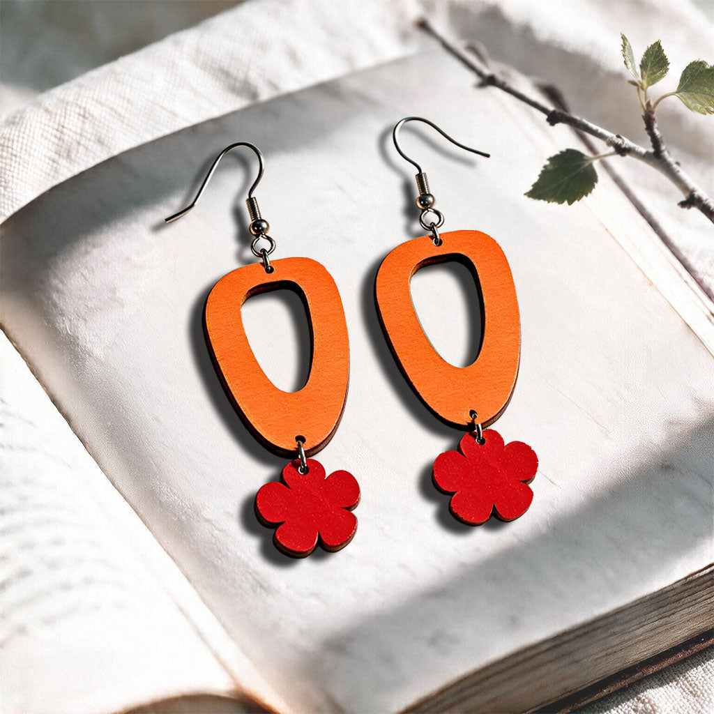Orange and red Luototar plywood earrings made in Finland, photographed on a vintage book in natural sunlight