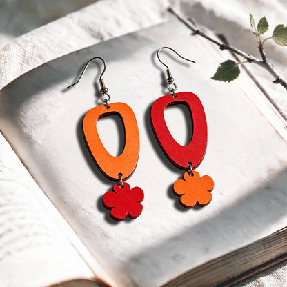 Red and Orange Luototar plywood earrings made in Finland, photographed on a vintage book in natural sunlight